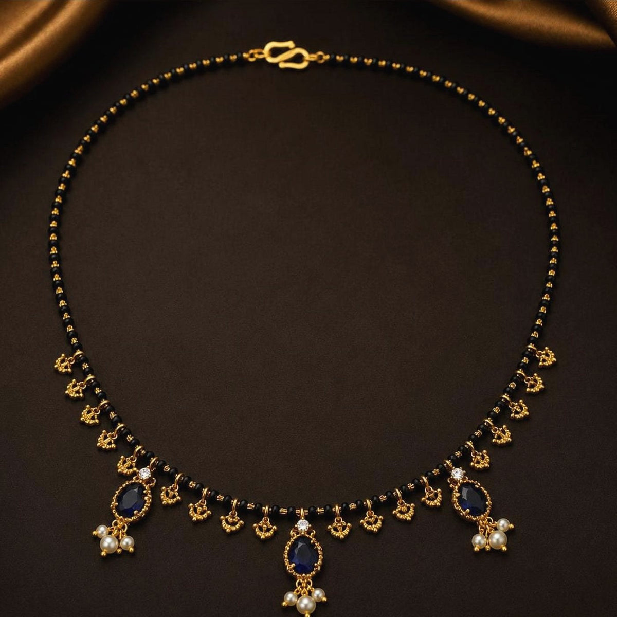 Black bead mangalsutra with a sapphire-blue toned pendant and clear-stone surround, front view