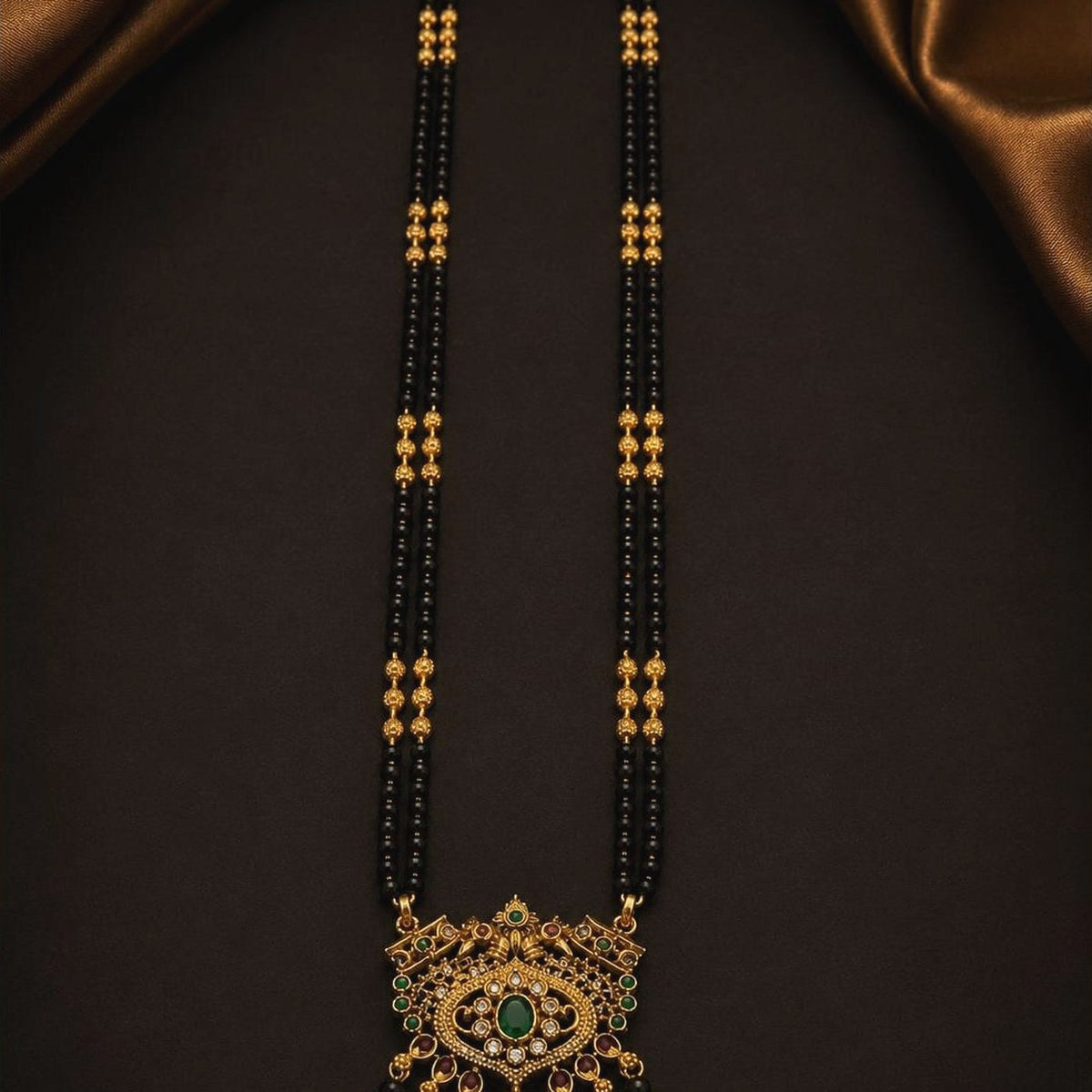Long double-strand black bead mangalsutra with an ornate emerald-toned pendant, front view
