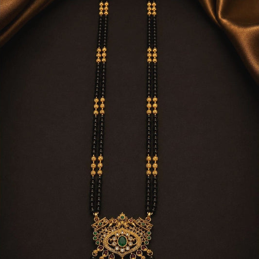 Long double-strand black bead mangalsutra with an ornate emerald-toned pendant, front view