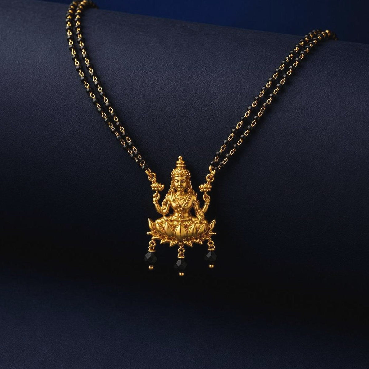 Black bead mangalsutra with a Lakshmi pendant and pearl-style drops, front view