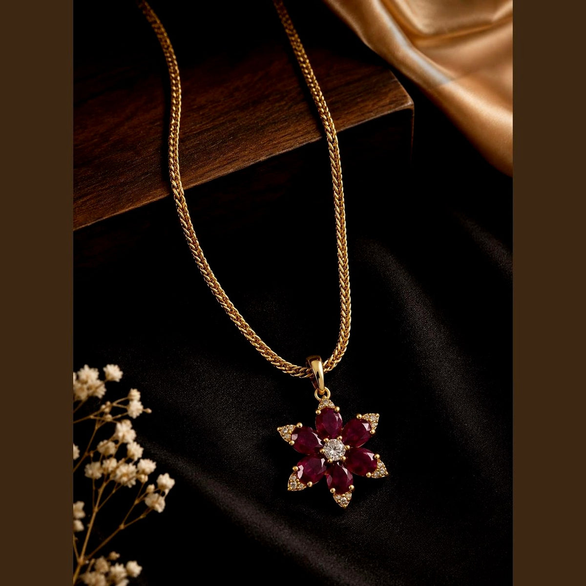 Gold-toned chain with a ruby-toned and clear-stone floral pendant, front view